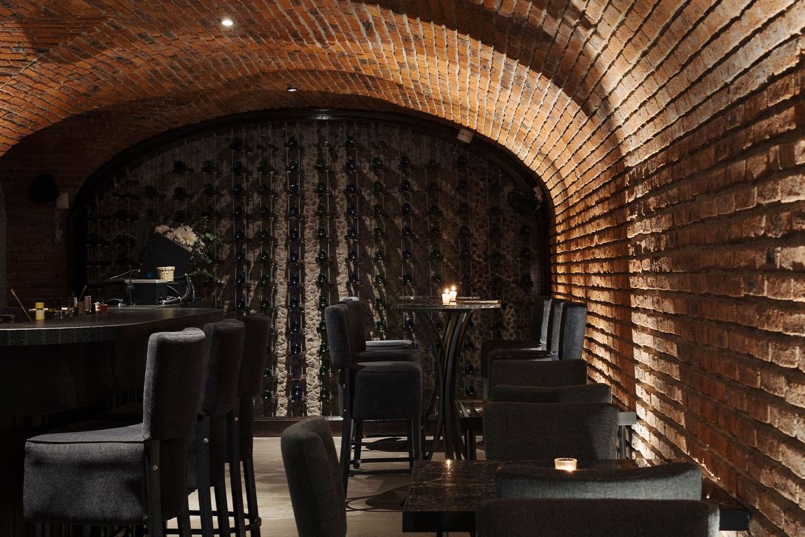 Una habitación oscura con una pared de ladrillos y mesas y sillas