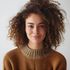 A woman with curly hair is wearing a brown sweater