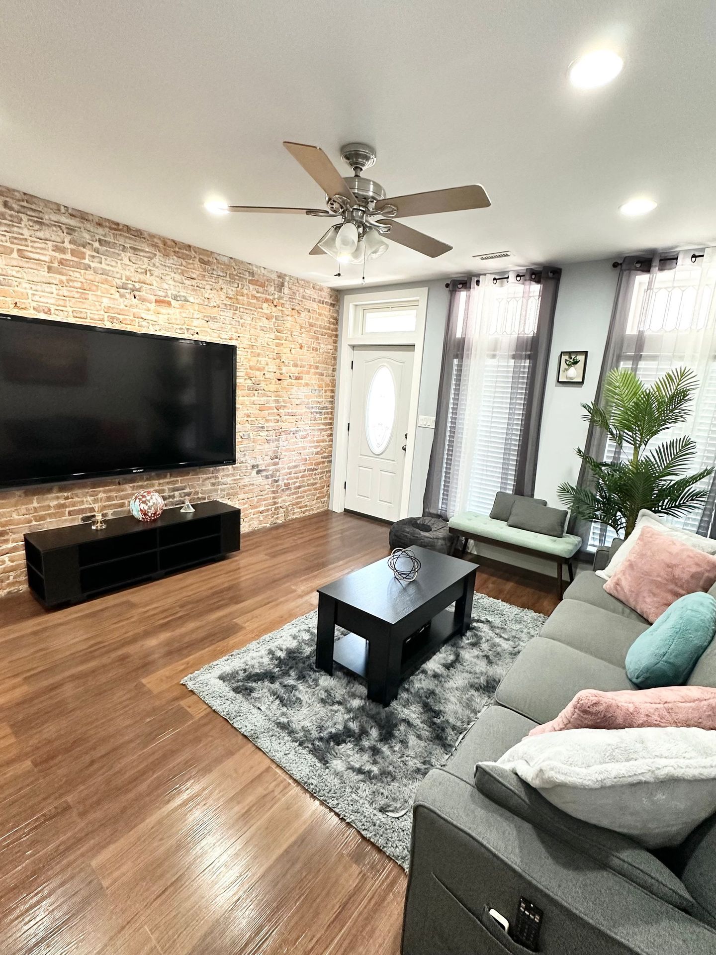 A living room with a couch , coffee table , television and ceiling fan.