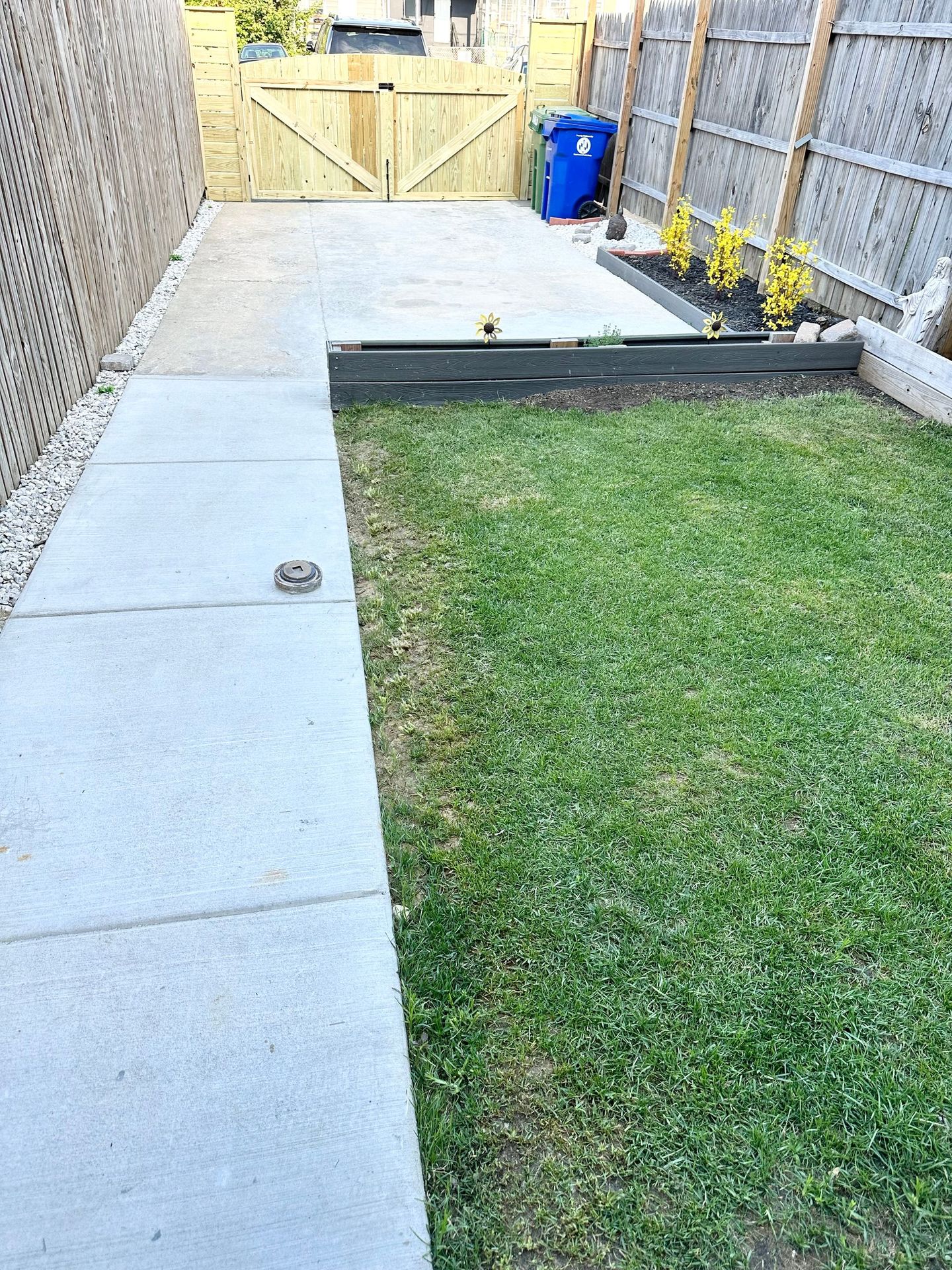 There is a concrete walkway leading to a lush green yard.