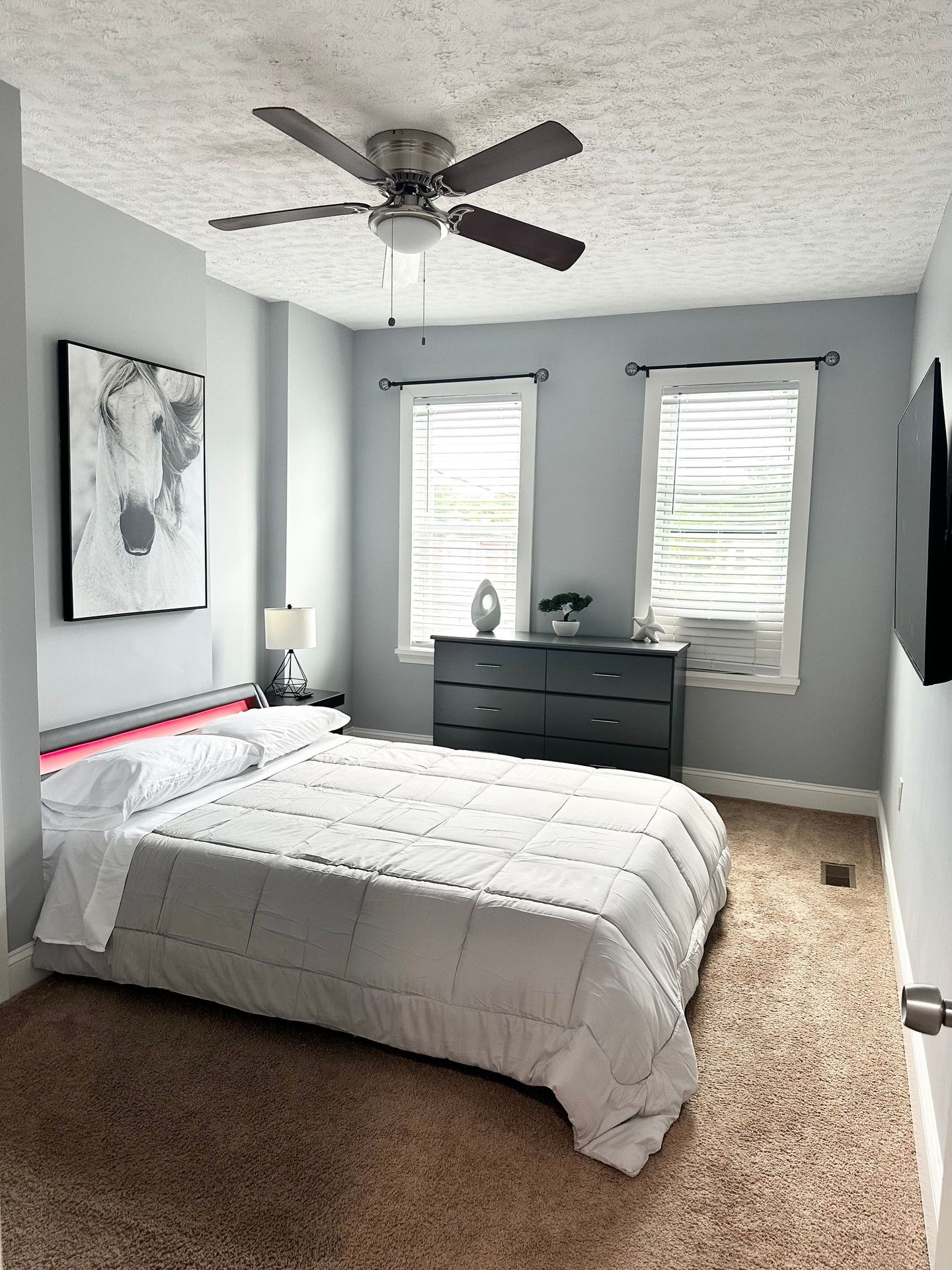 A bedroom with a bed , dresser , and ceiling fan.