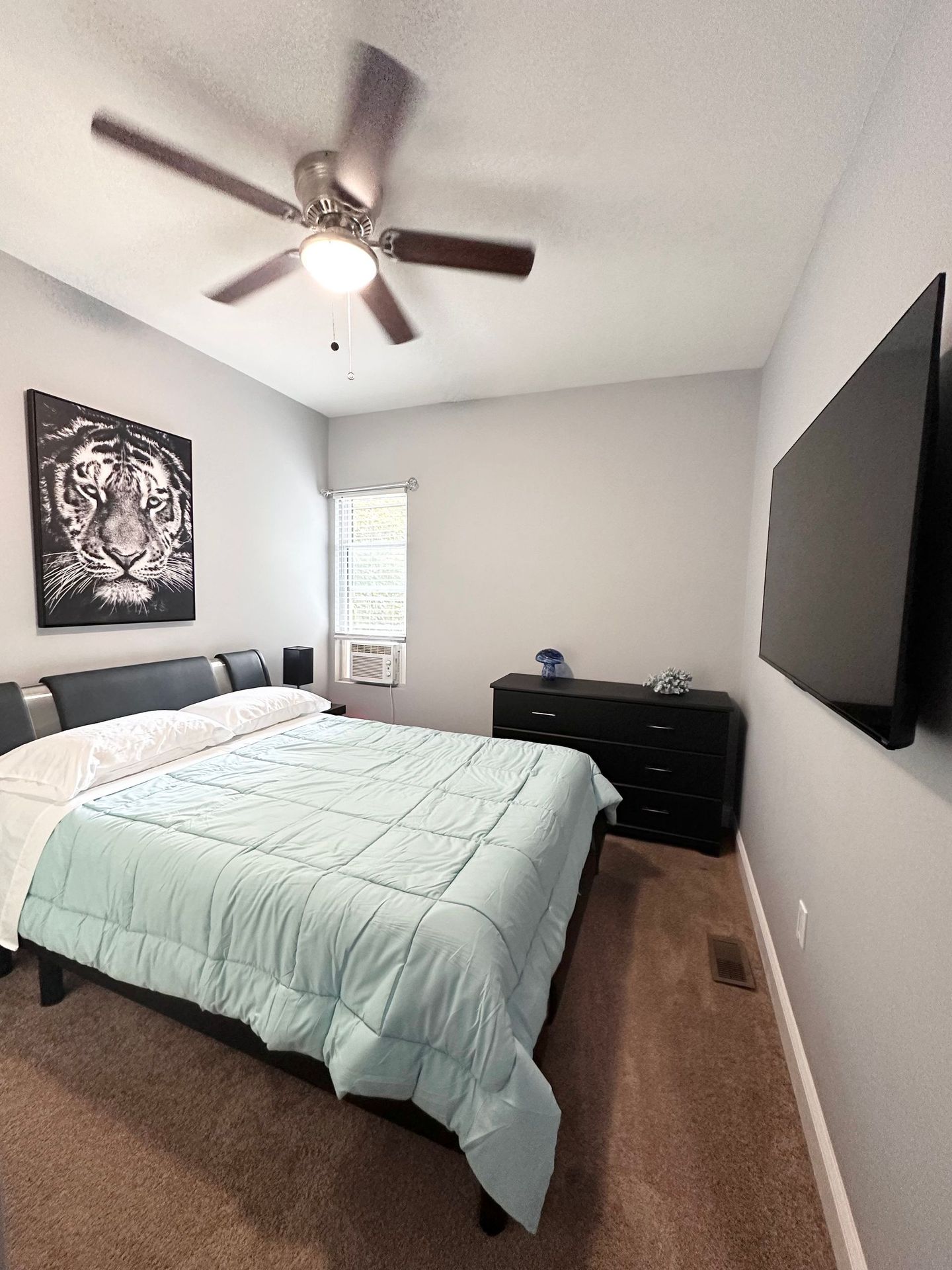 A bedroom with a large bed and a flat screen tv on the wall.