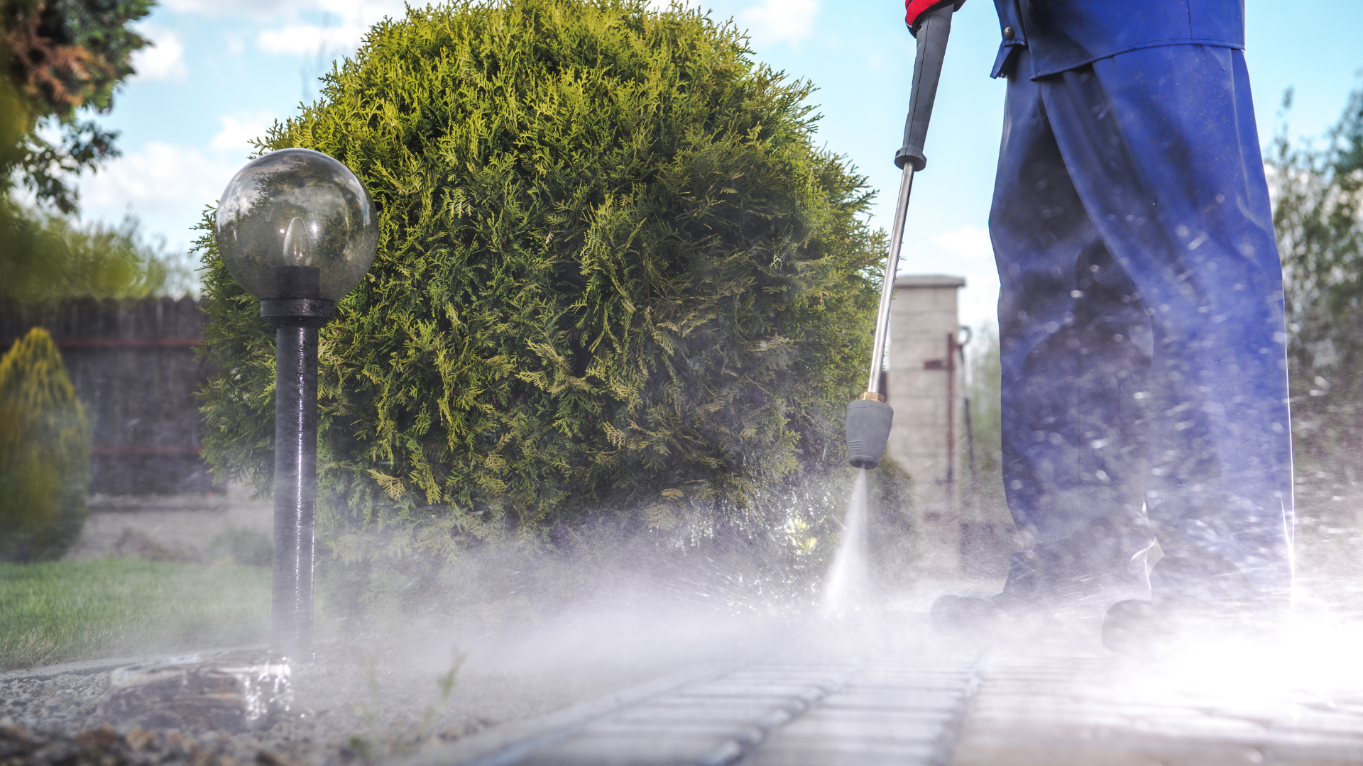 A man is using a high pressure washer to clean a patio.