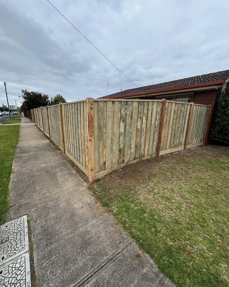 Wooden Fence Is Sitting on The Side of A Sidewalk Next to A House — Flintoff Constructions in Charlemont, VIC
