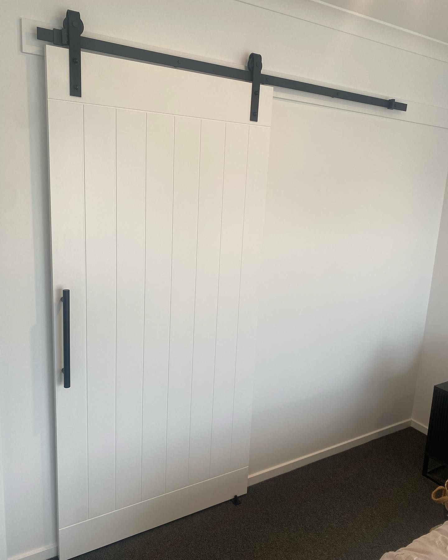 A White Sliding Barn Door Is Hanging on A White Wall in A Bedroom — Flintoff Constructions in Charlemont, VIC
