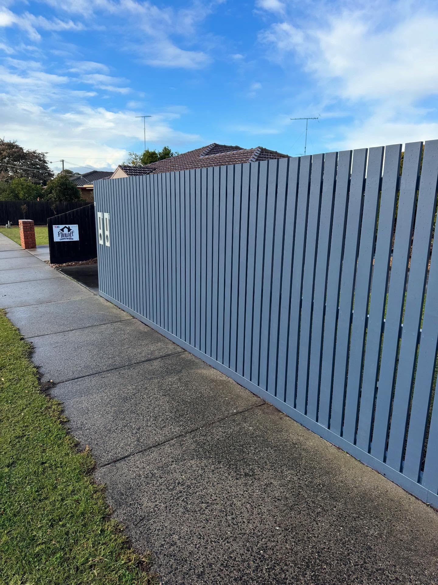 A Blue Fence Is Sitting Next to A Brick Wall — Flintoff Constructions in Charlemont, VIC