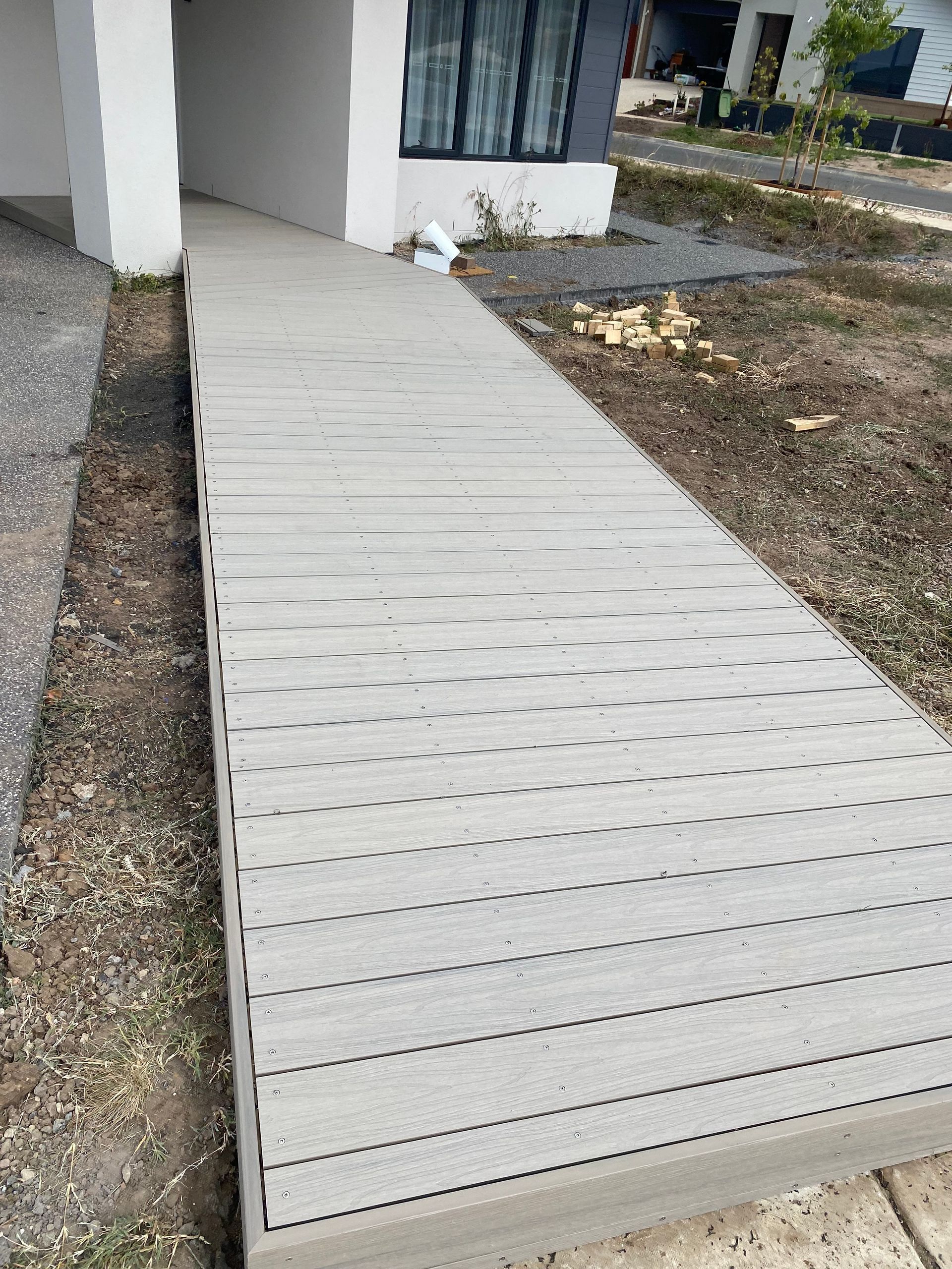 A Wooden Deck Is Sitting on The Side of A Building Next to A Potted Plant — Flintoff Constructions in Charlemont, VIC