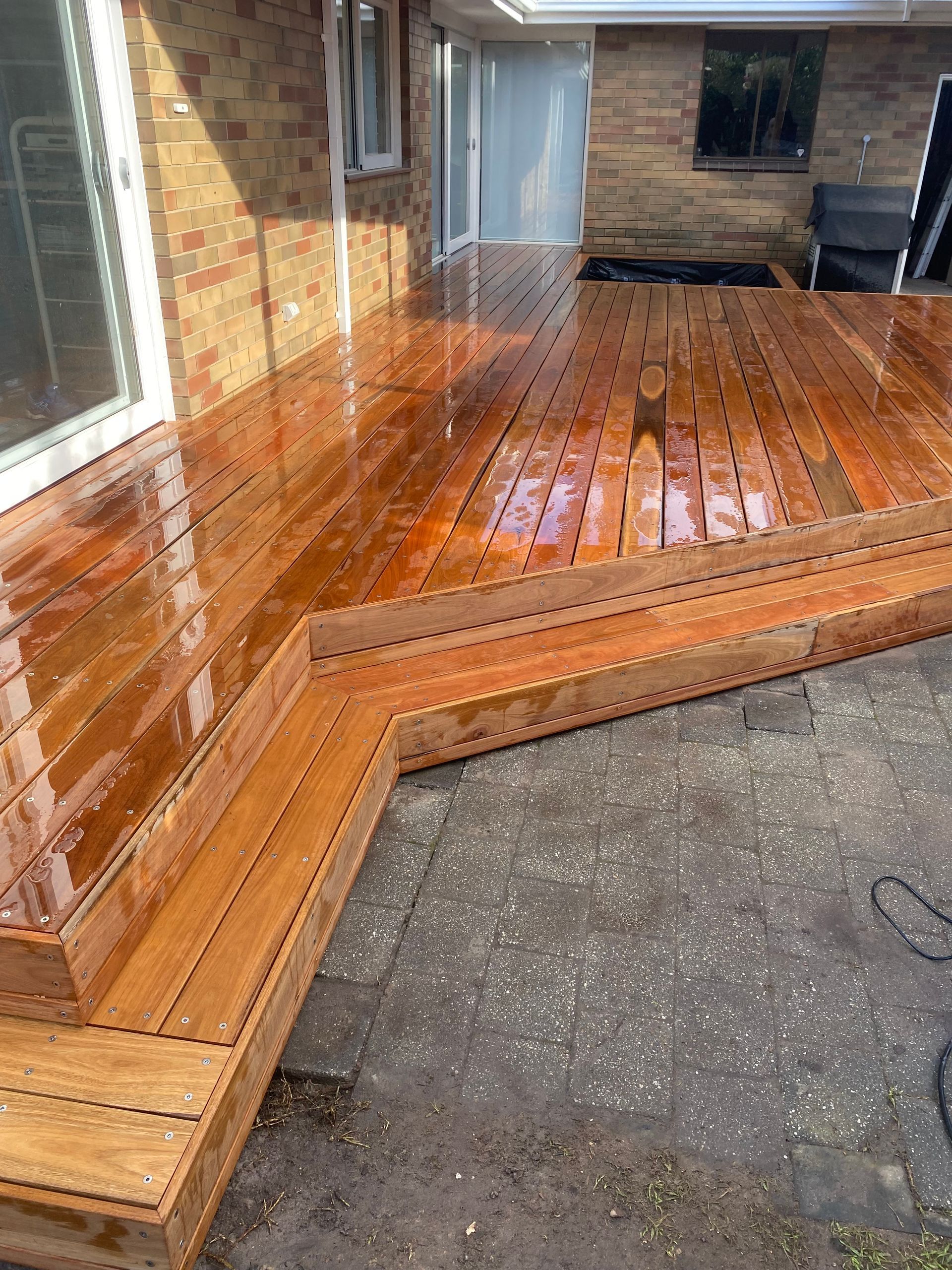 A Wooden Deck Is Sitting on Top of A Concrete Walkway Next to A Door — Flintoff Constructions in Charlemont, VIC