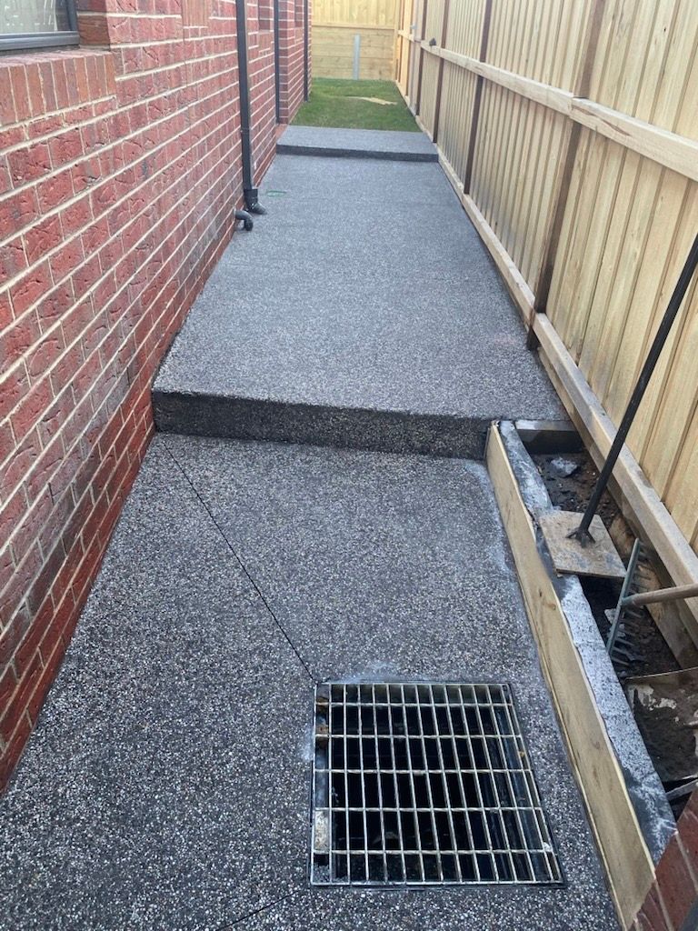 Man Is Using a Trowel to Spread Concrete on A Sidewalk — Flintoff Constructions in Charlemont, VIC