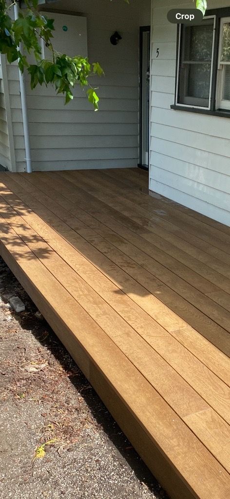 A Wooden Deck with Stairs Is Sitting in The Grass in Front of A House — Flintoff Constructions in Charlemont, VIC