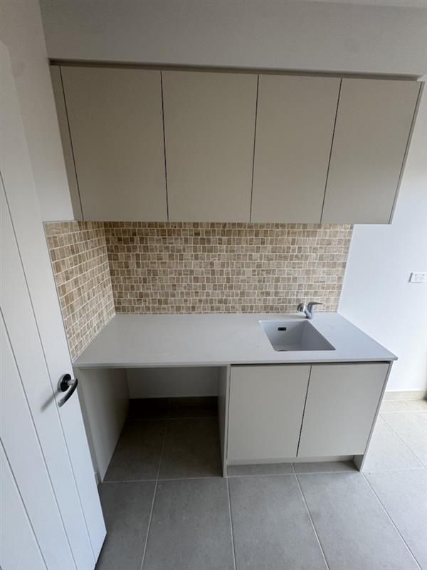 A Person Is Laying Tiles on The Floor with A Trowel — Flintoff Constructions in Charlemont, VIC