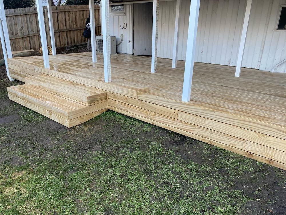 Light Grey Wooden Deck with A Brick Wall in The Background — Flintoff Constructions in Charlemont, VIC