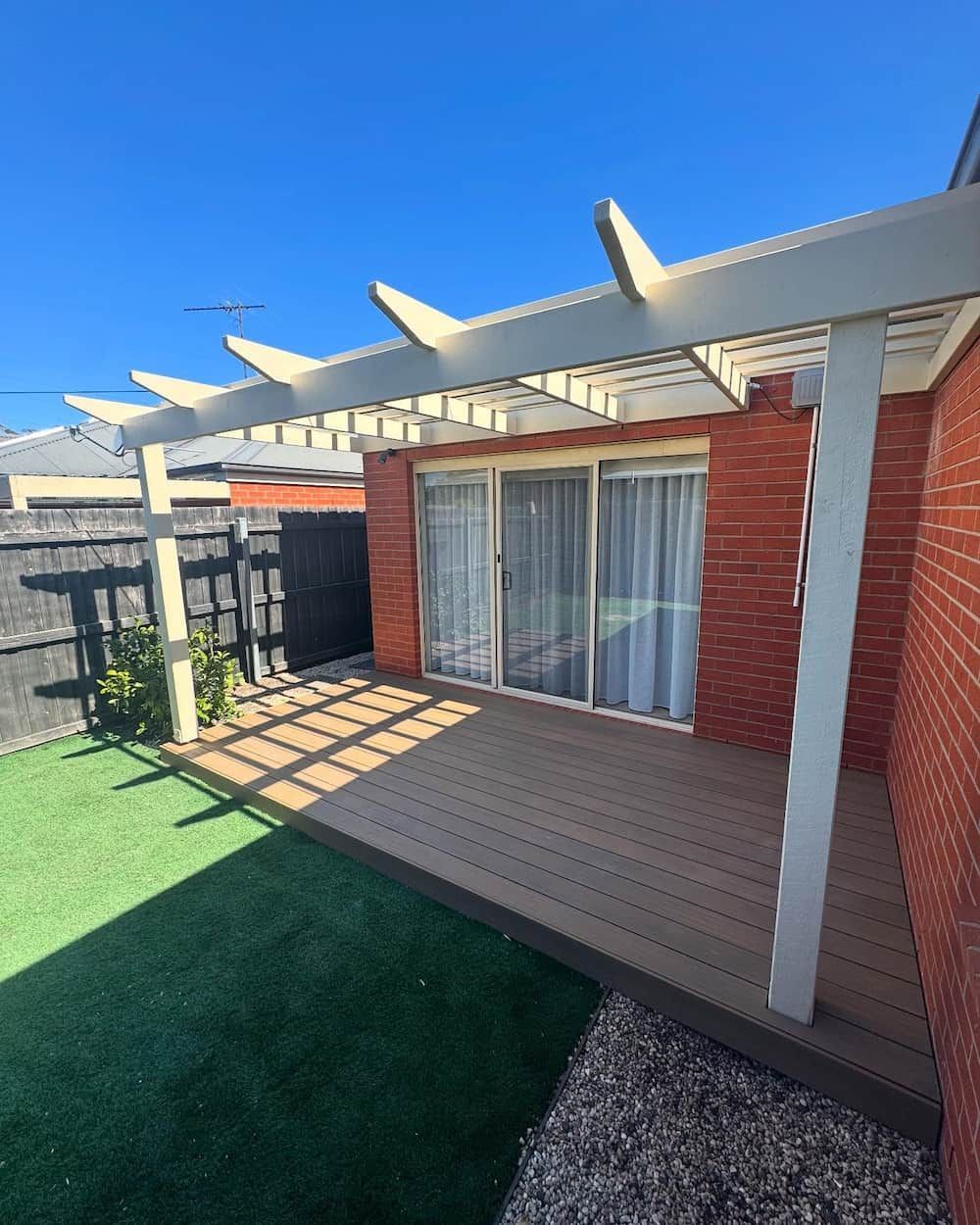 A house with orange brick walls and a  white pergola and wooden deck — Flintoff Constructions in Charlemont, VIC