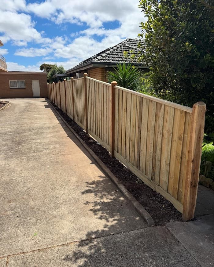 A Wooden Fence Surrounds a Driveway in Front of A House — Flintoff Constructions in Charlemont, VIC
