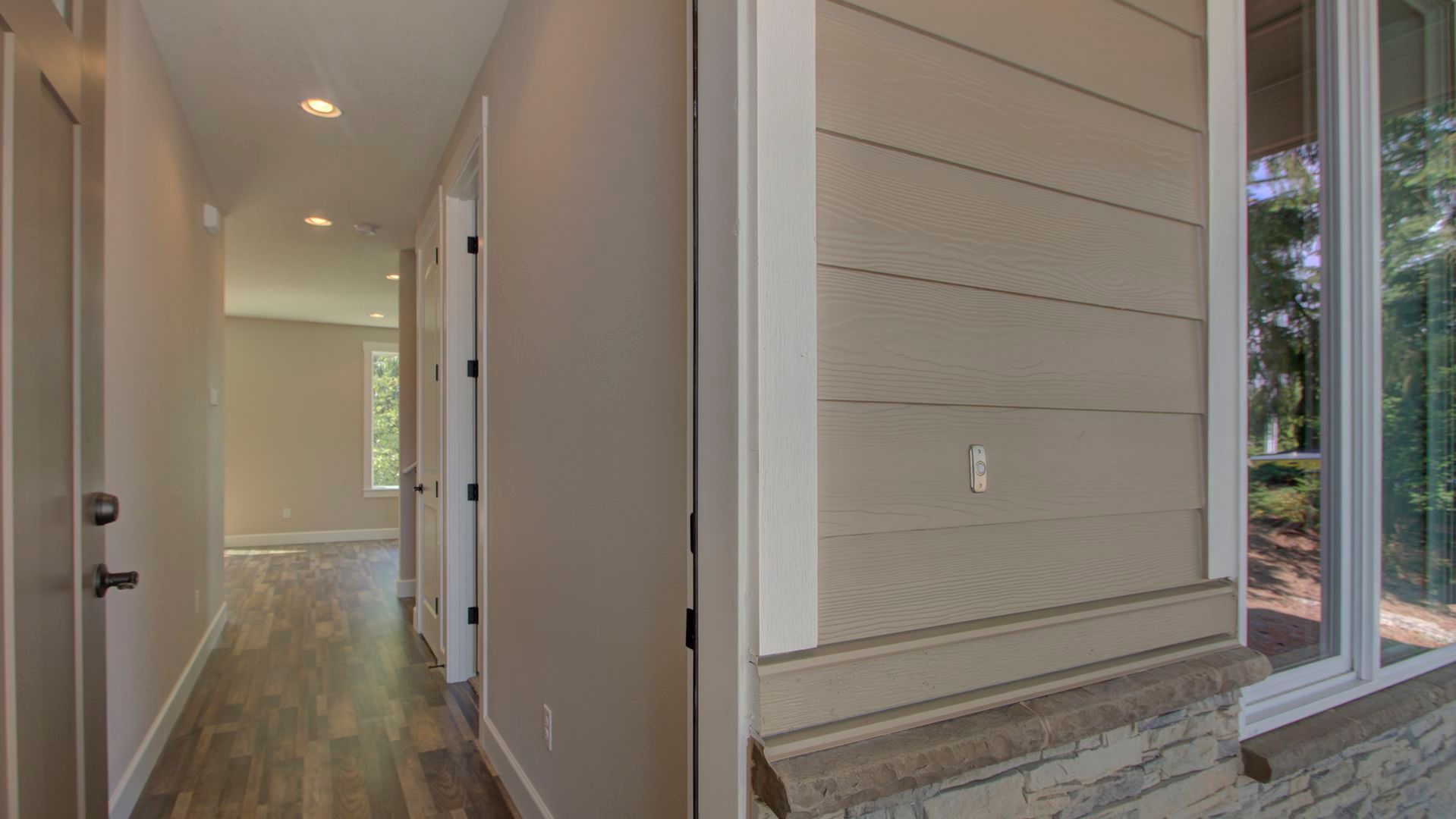 A hallway in a house with hardwood floors and a window.