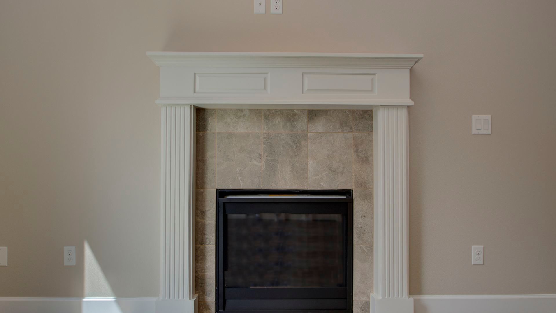 A fireplace with a white mantle in a living room.