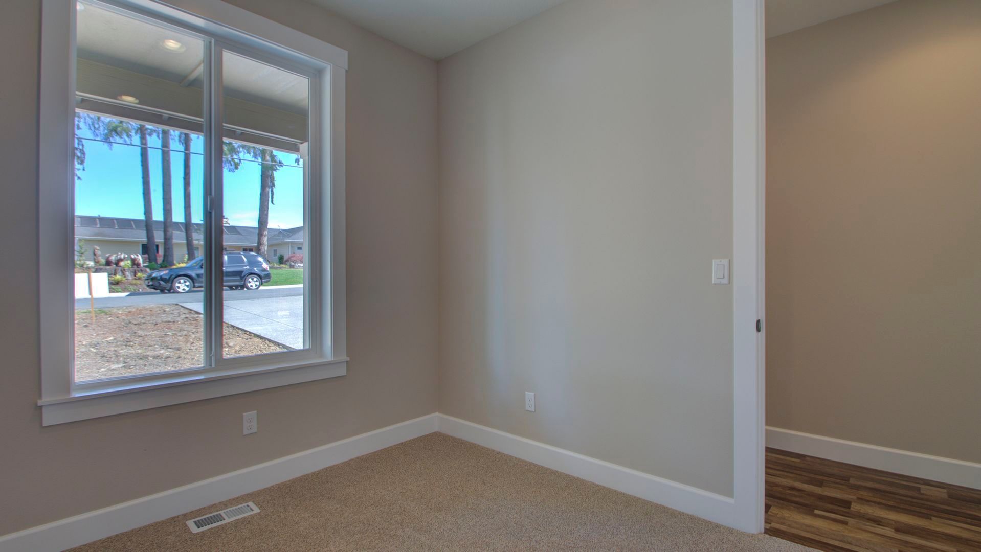 An empty room with a large window and a sliding glass door.