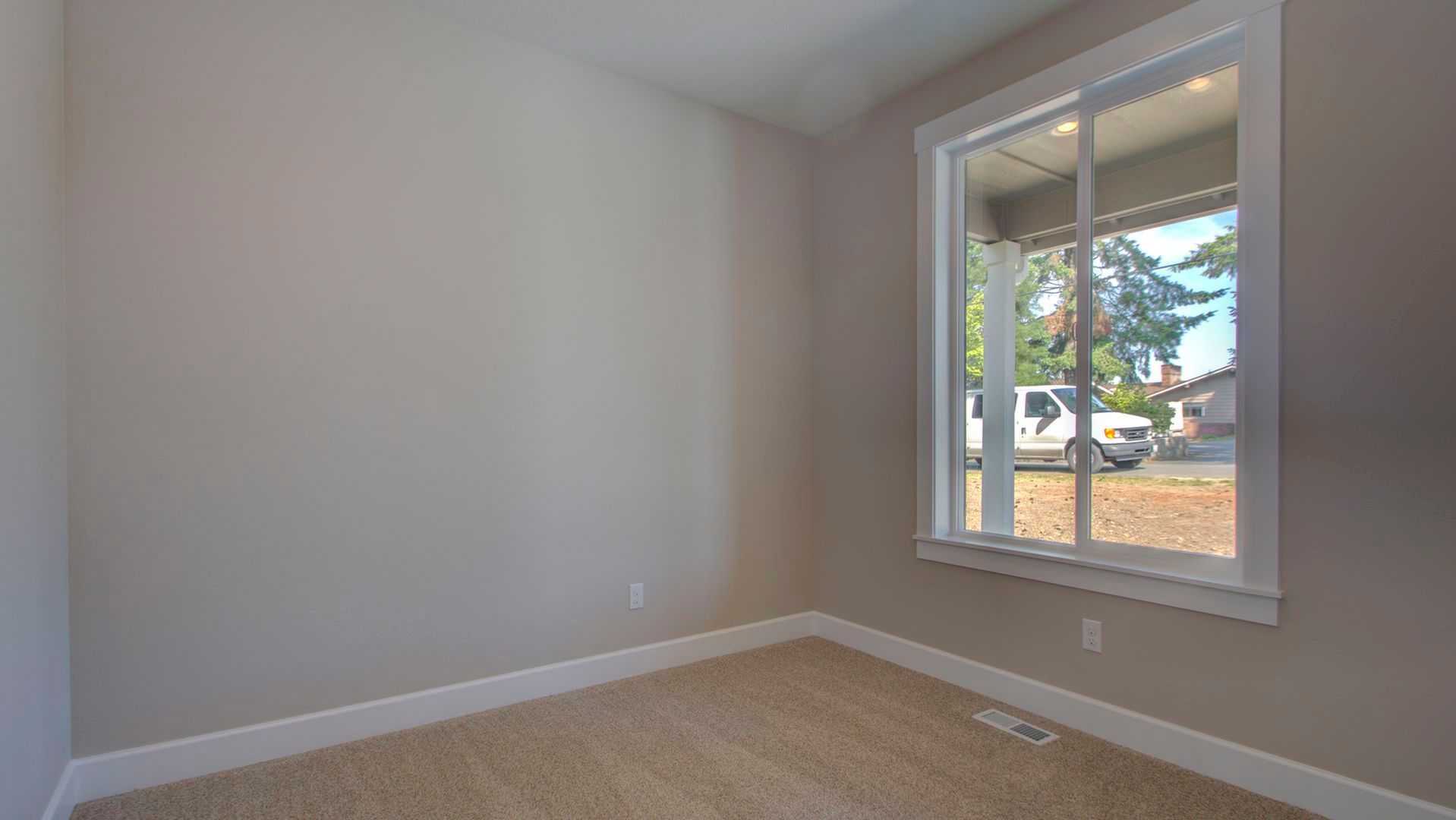 An empty room with a large window and a sliding glass door.