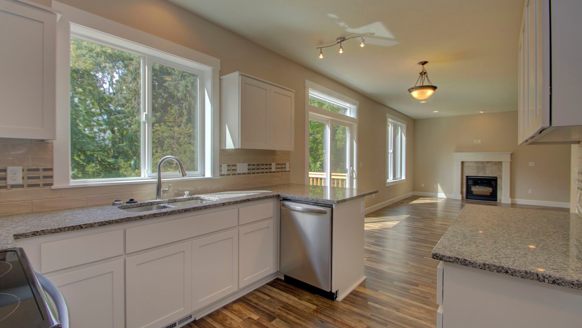 An empty kitchen in a new home with granite counter tops and white cabinets.