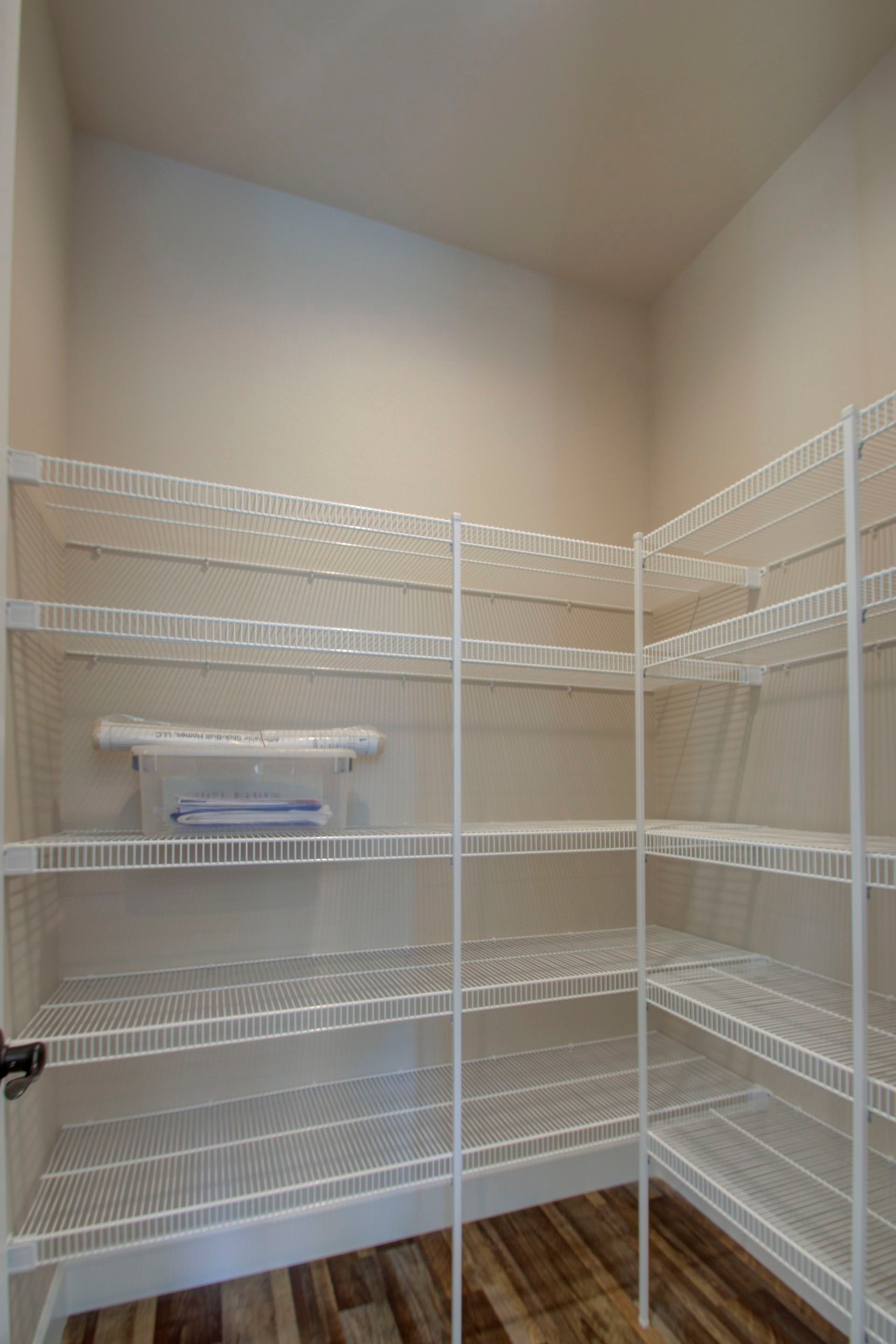 A pantry with lots of shelves and a wooden floor.