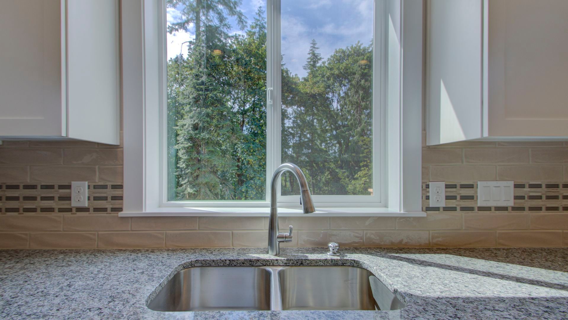A kitchen sink with a faucet and a window in the background.