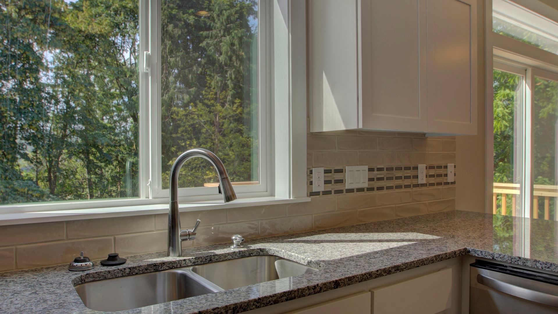 A kitchen with a sink and a window with trees in the background.