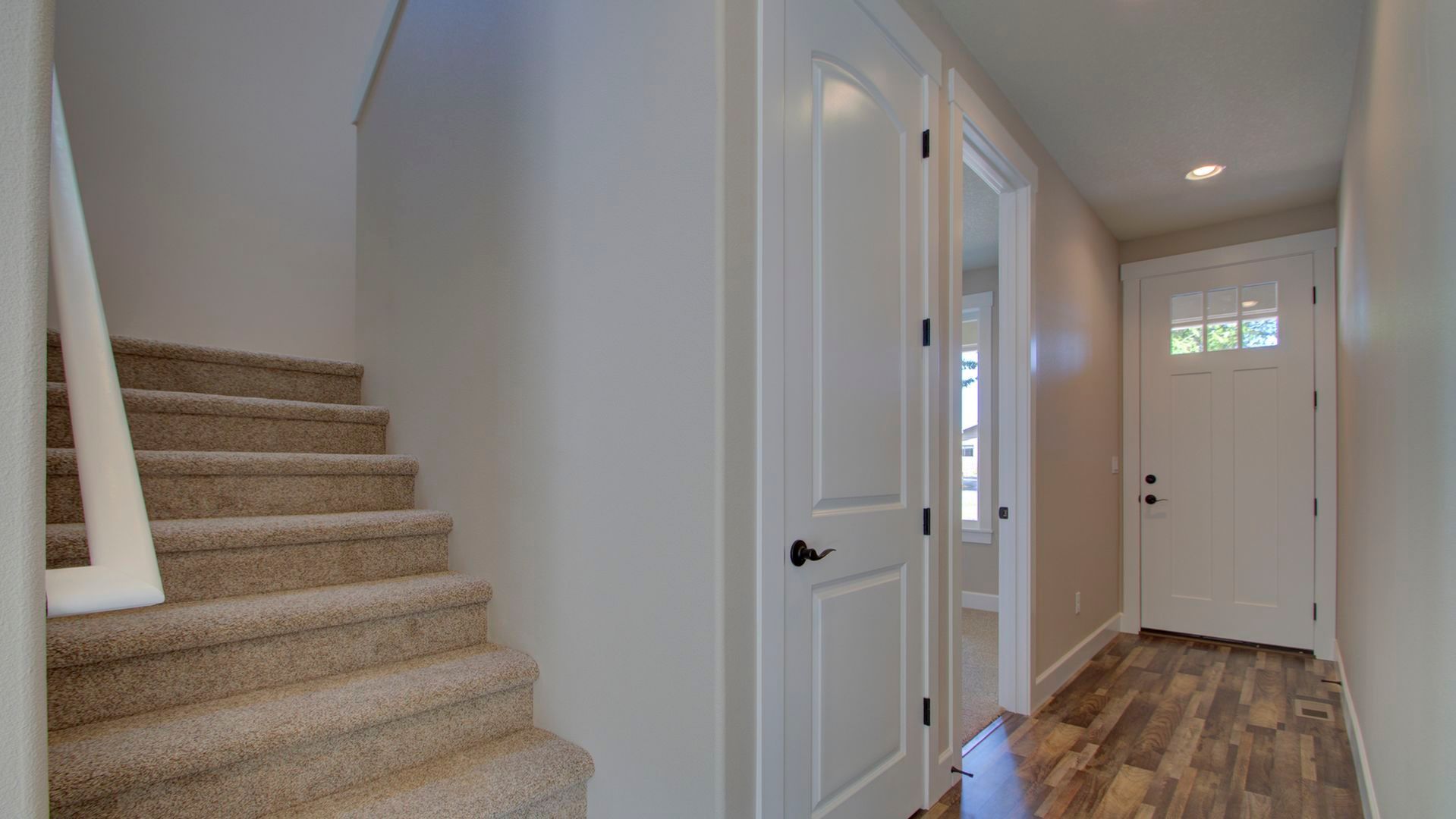 A hallway with stairs leading up to the second floor and a door.