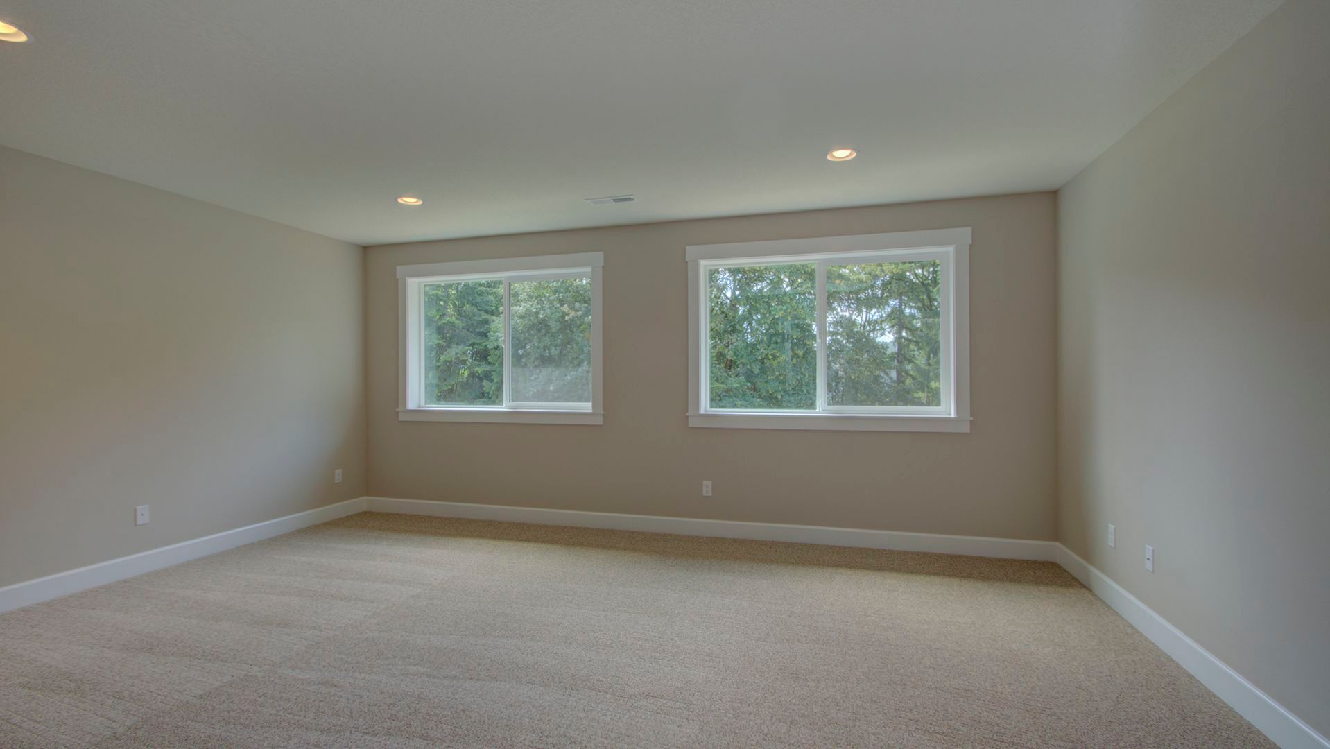 An empty room with two windows and a carpeted floor.