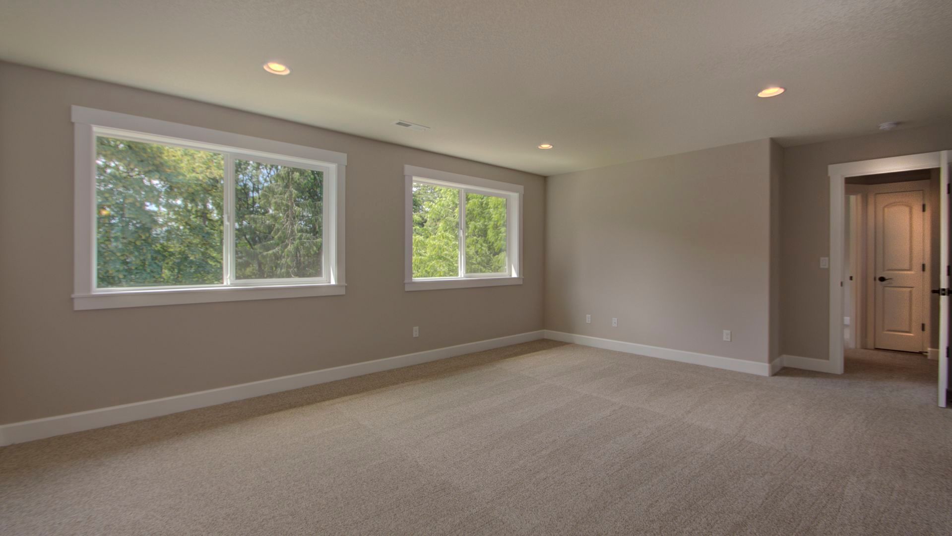 An empty room with two windows and a carpeted floor.
