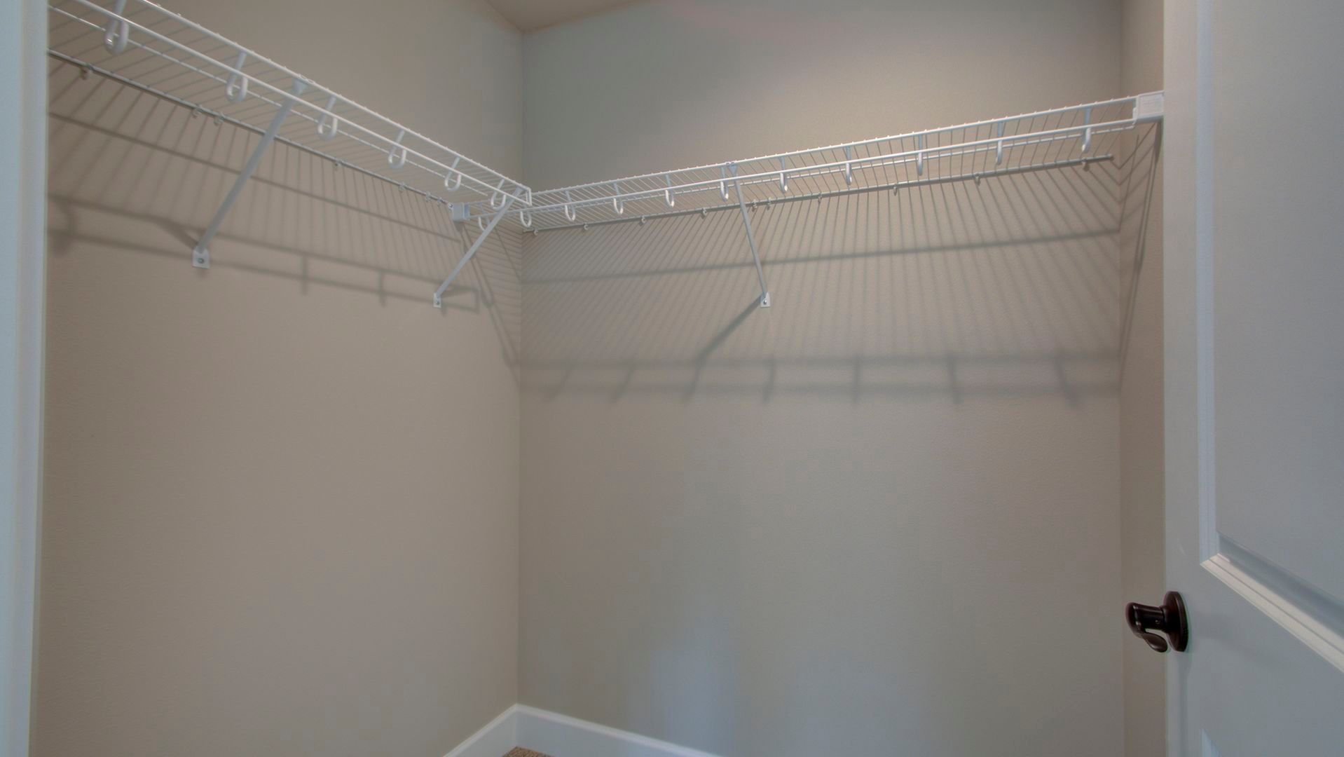 An empty walk in closet with wire shelves and a door.