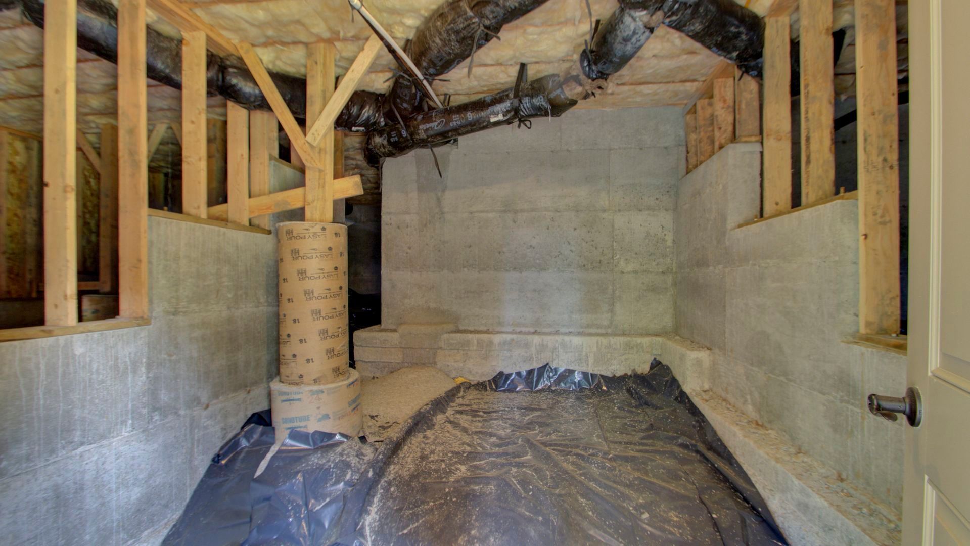An empty basement with a lot of pipes coming out of it.
