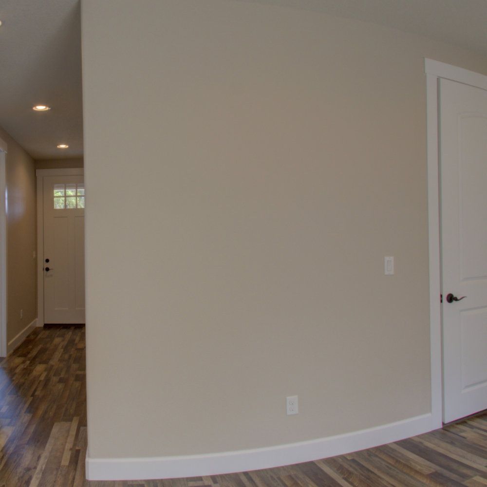 A hallway with a curved wall and a white door