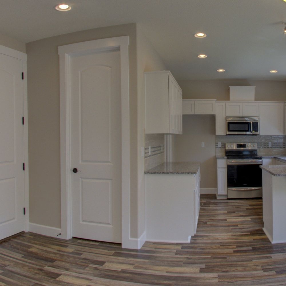 A kitchen with hardwood floors and white cabinets