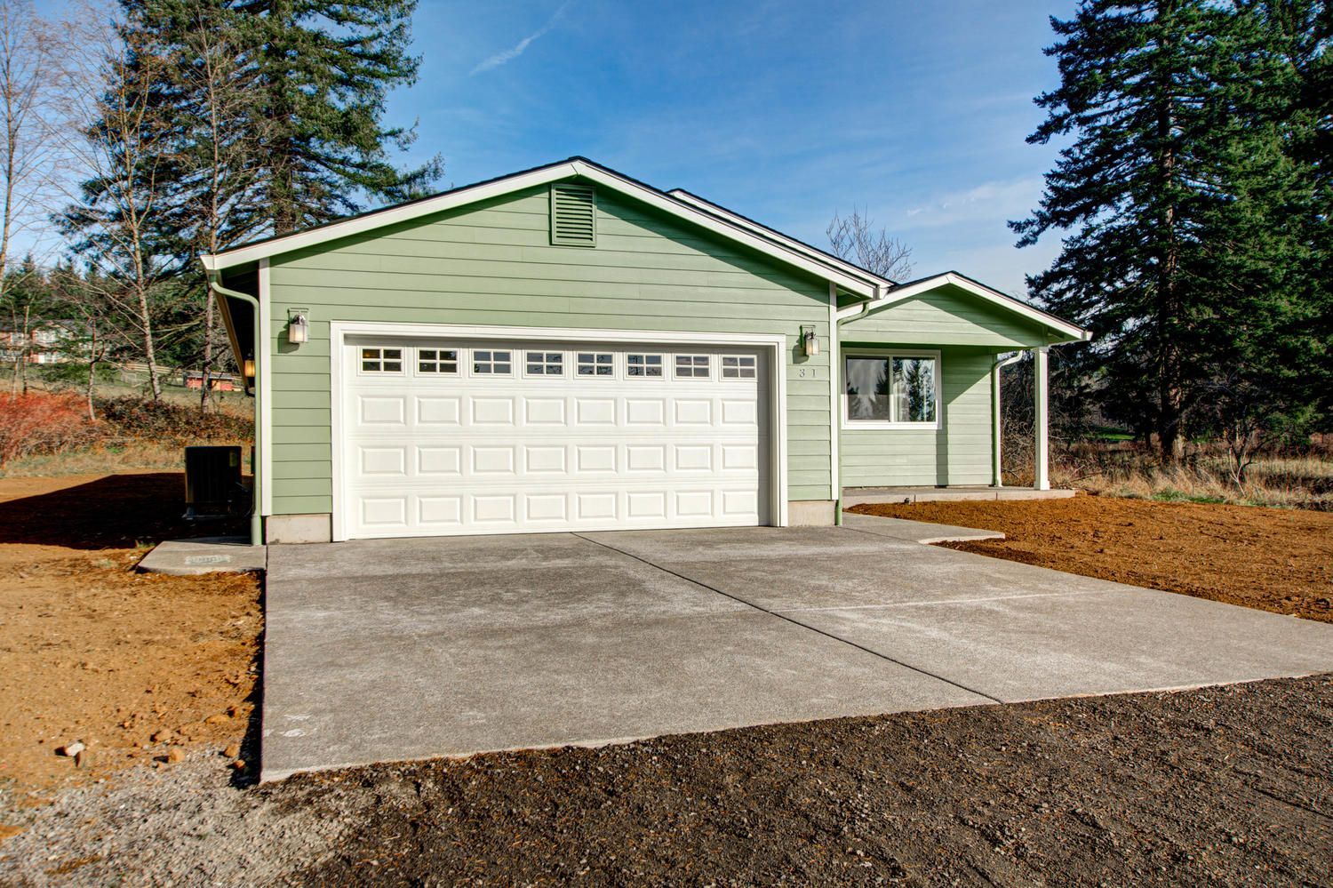 A green house with a white garage door