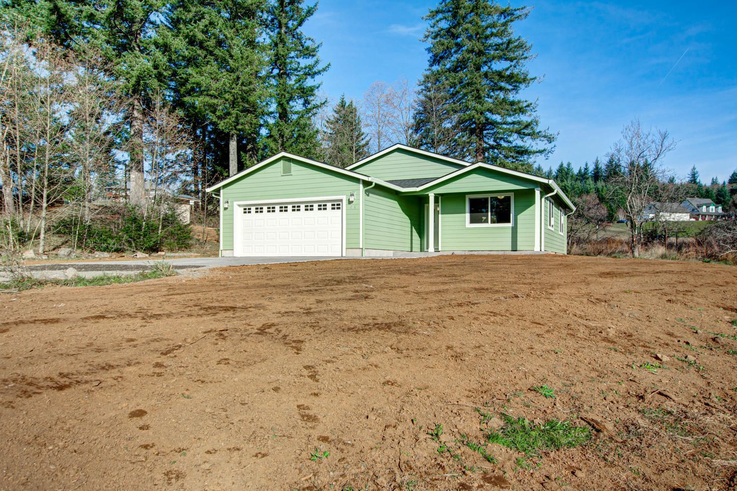 A green house is sitting in the middle of a dirt field.