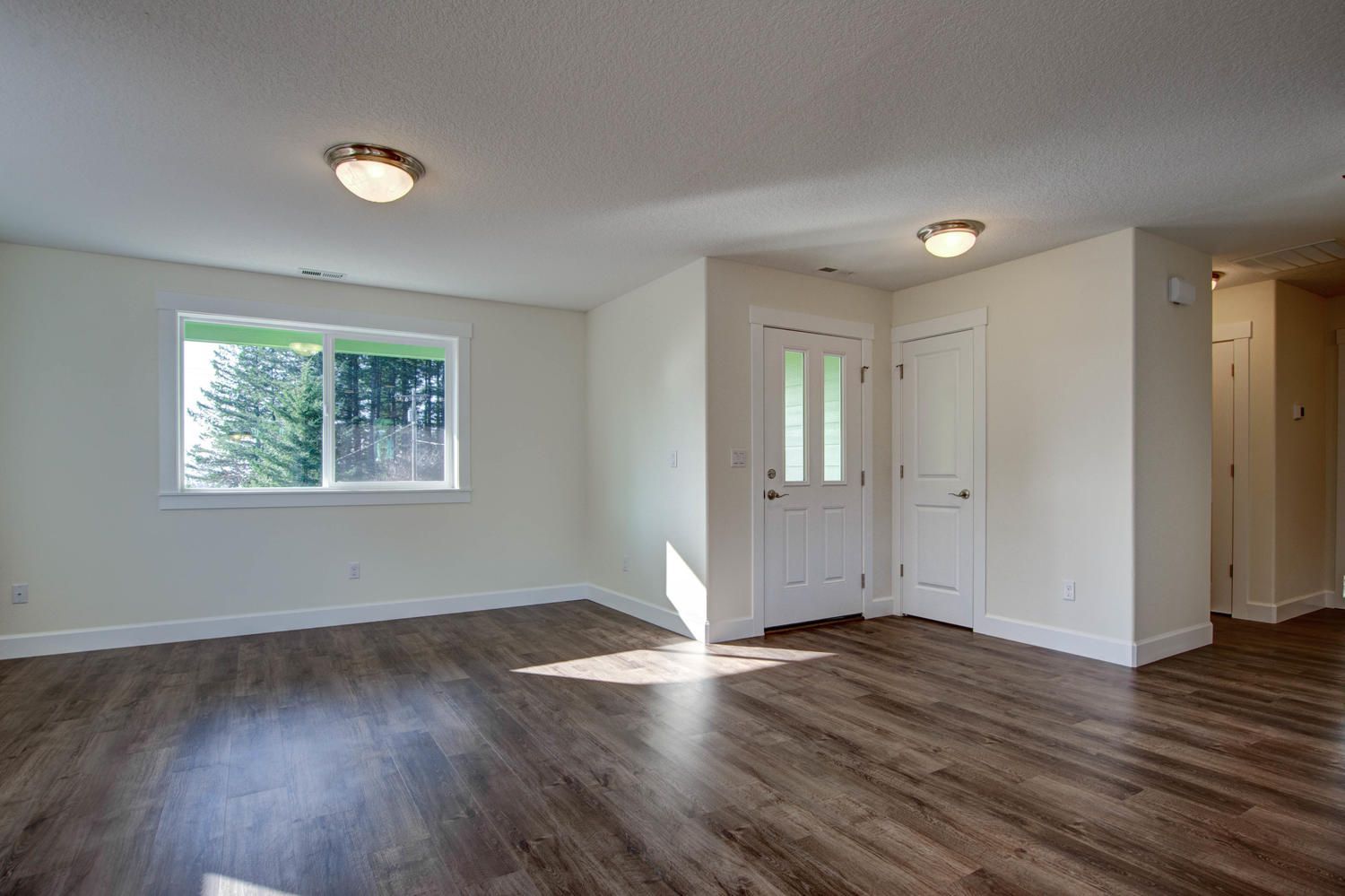 An empty living room with hardwood floors and a window.