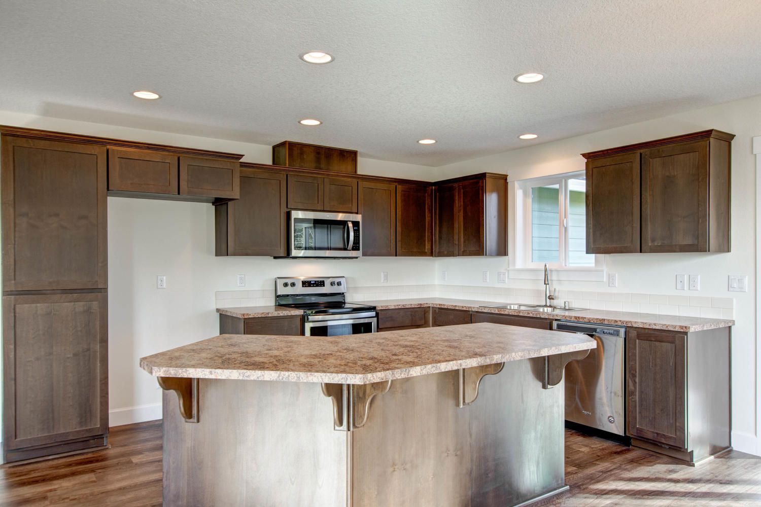A kitchen with wooden cabinets , granite counter tops , stainless steel appliances and a large island.