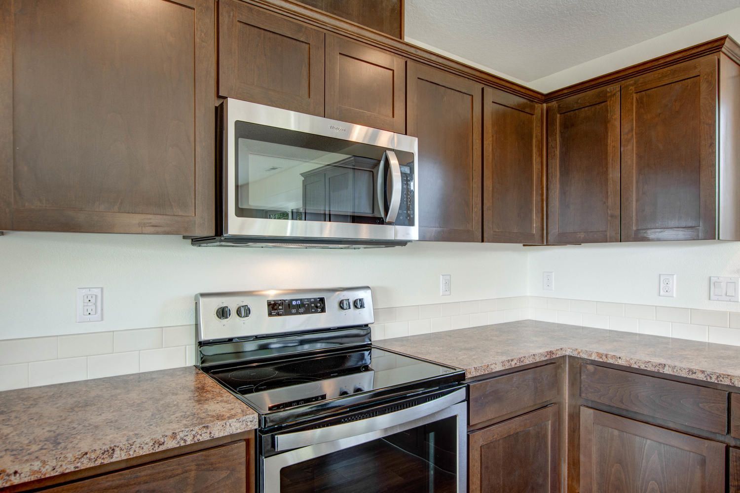 A kitchen with a stove , microwave , and granite counter tops.