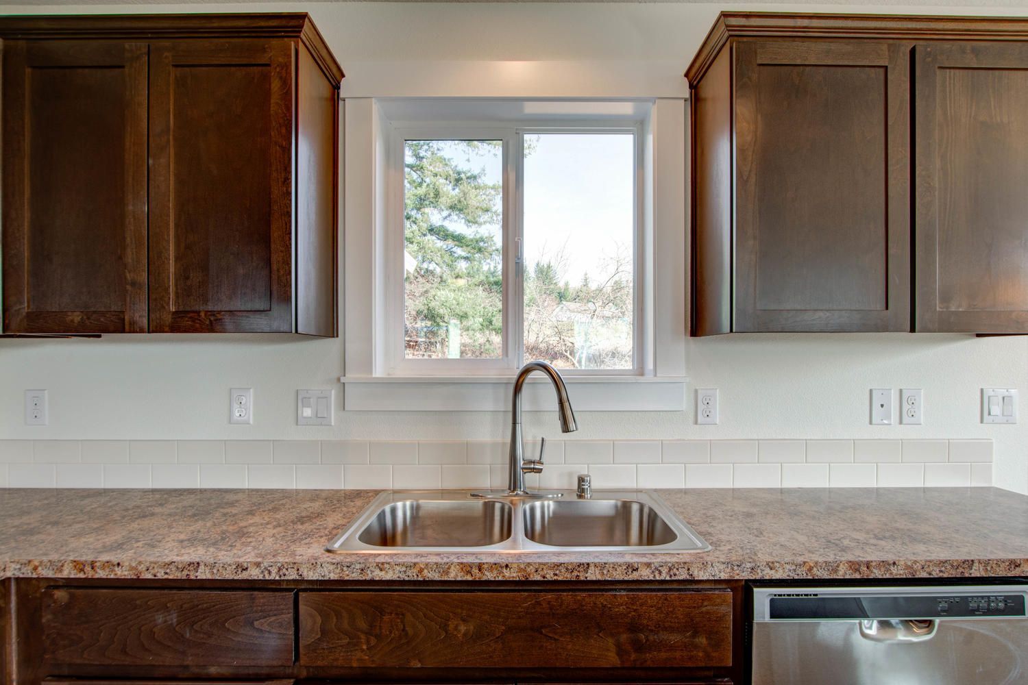 A kitchen with a sink , cabinets , and a window.