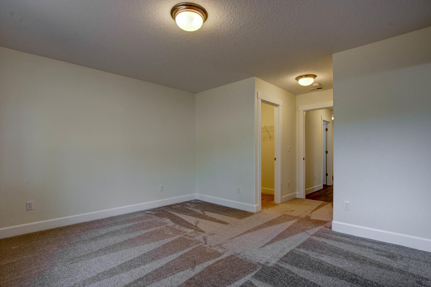 An empty bedroom with a carpeted floor and white walls.