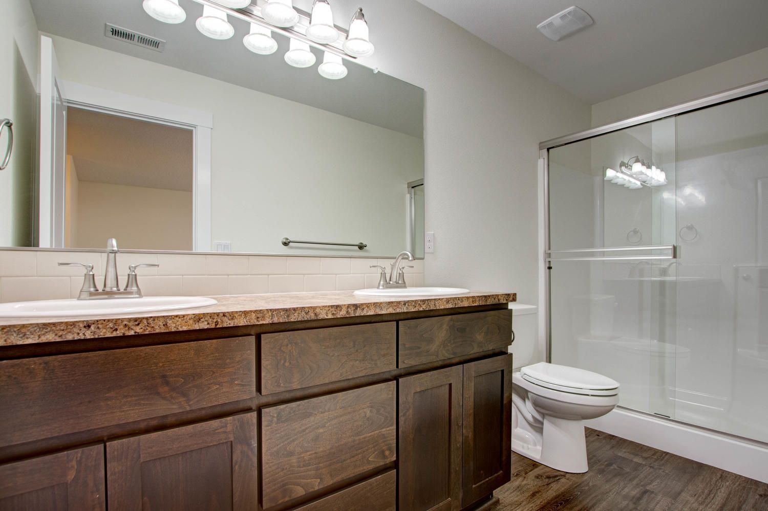 A bathroom with two sinks , a toilet and a shower.