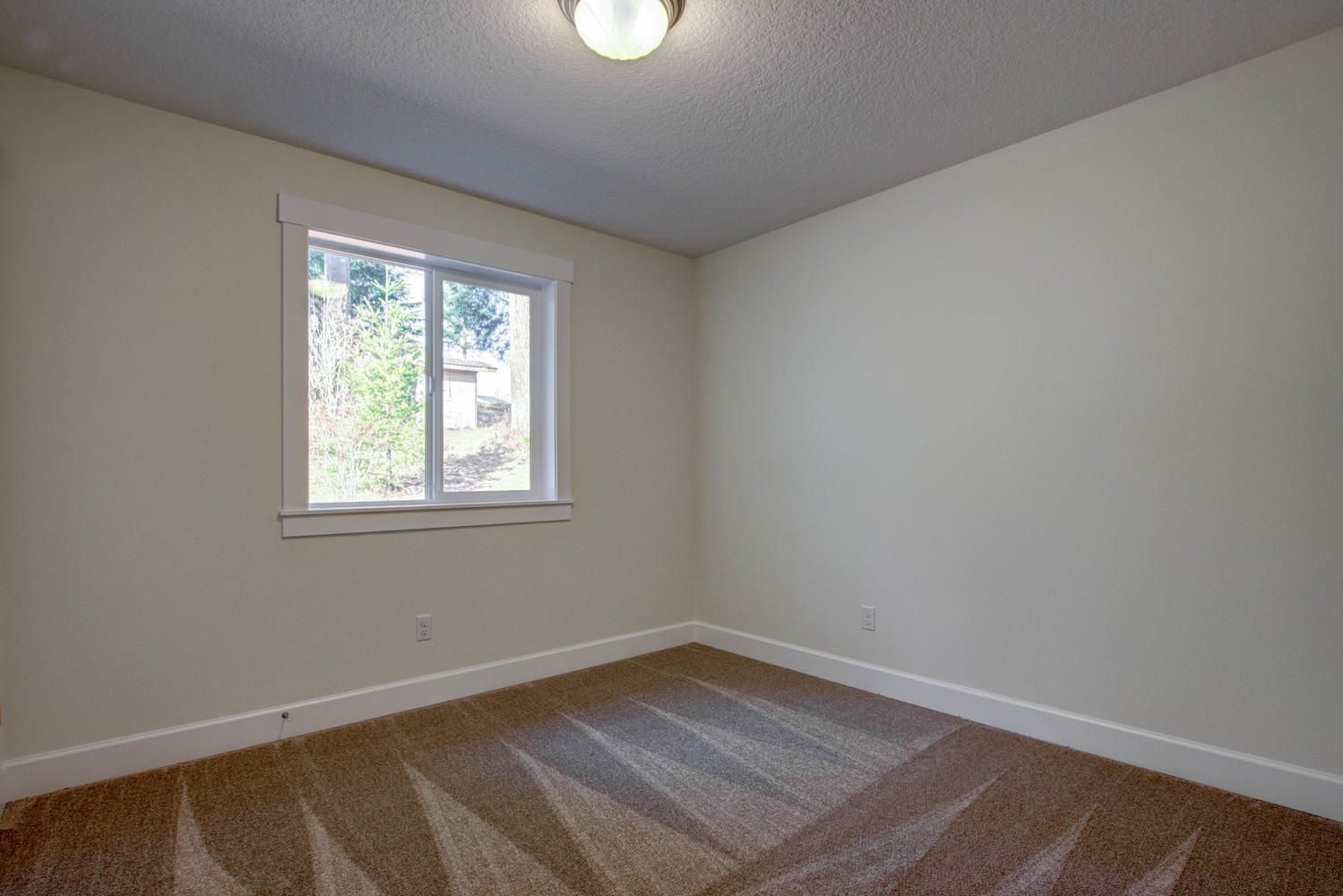 An empty bedroom with a window and a ceiling fan.