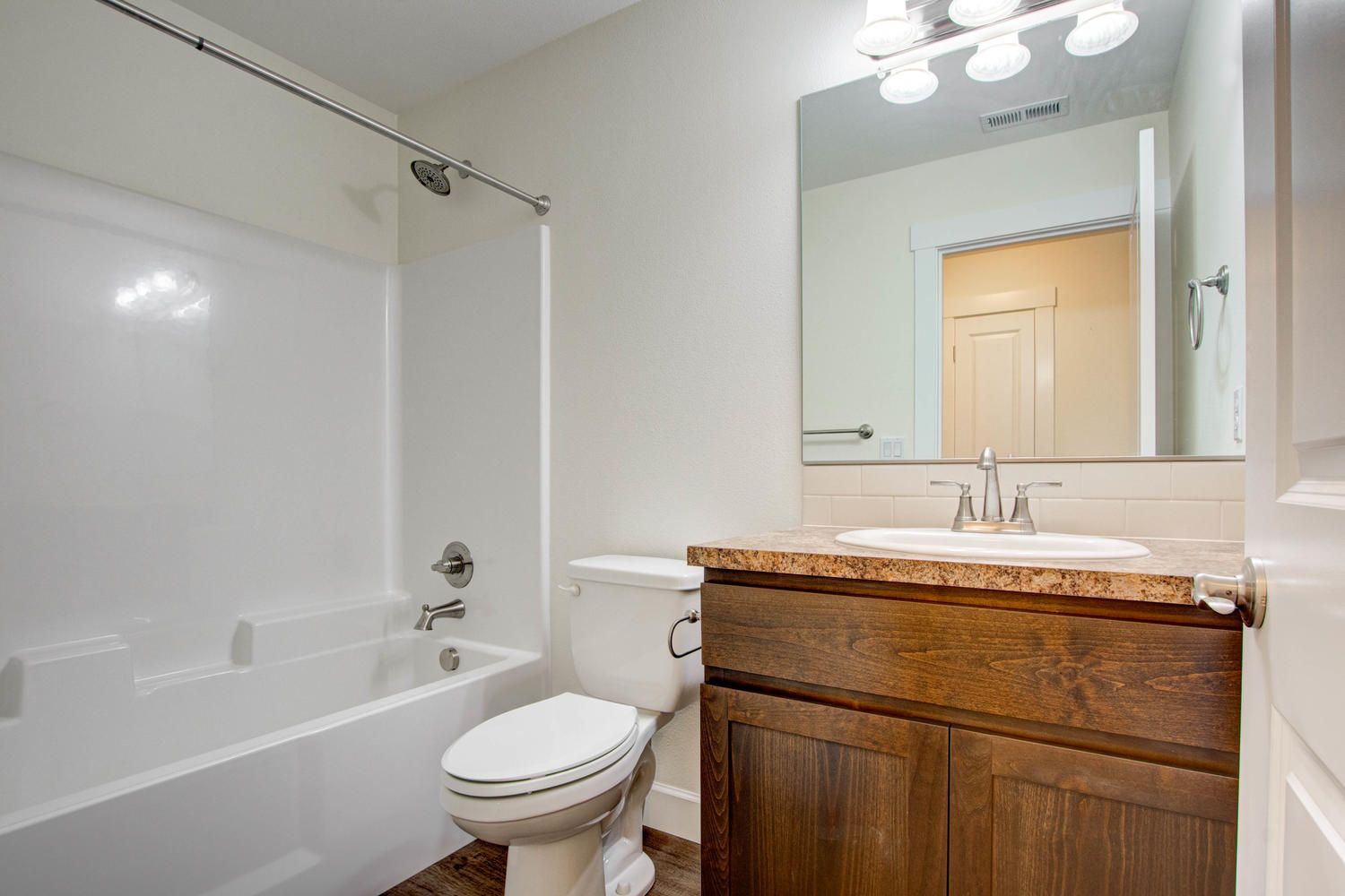 A bathroom with a toilet , sink , tub and mirror.