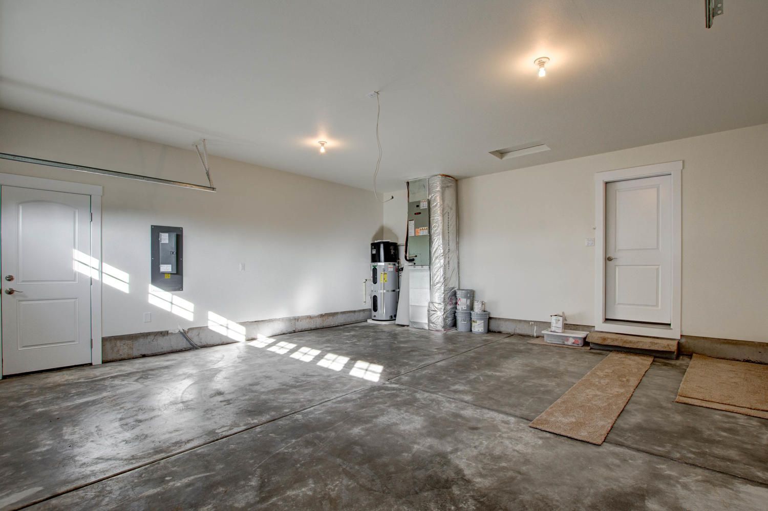 A large empty garage with a concrete floor and white walls.
