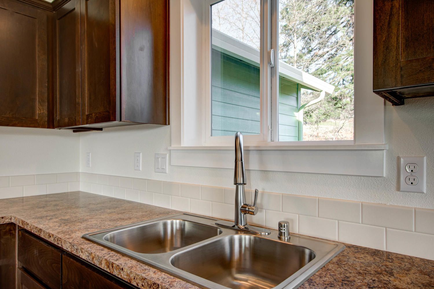 A kitchen with a stainless steel sink and a window.
