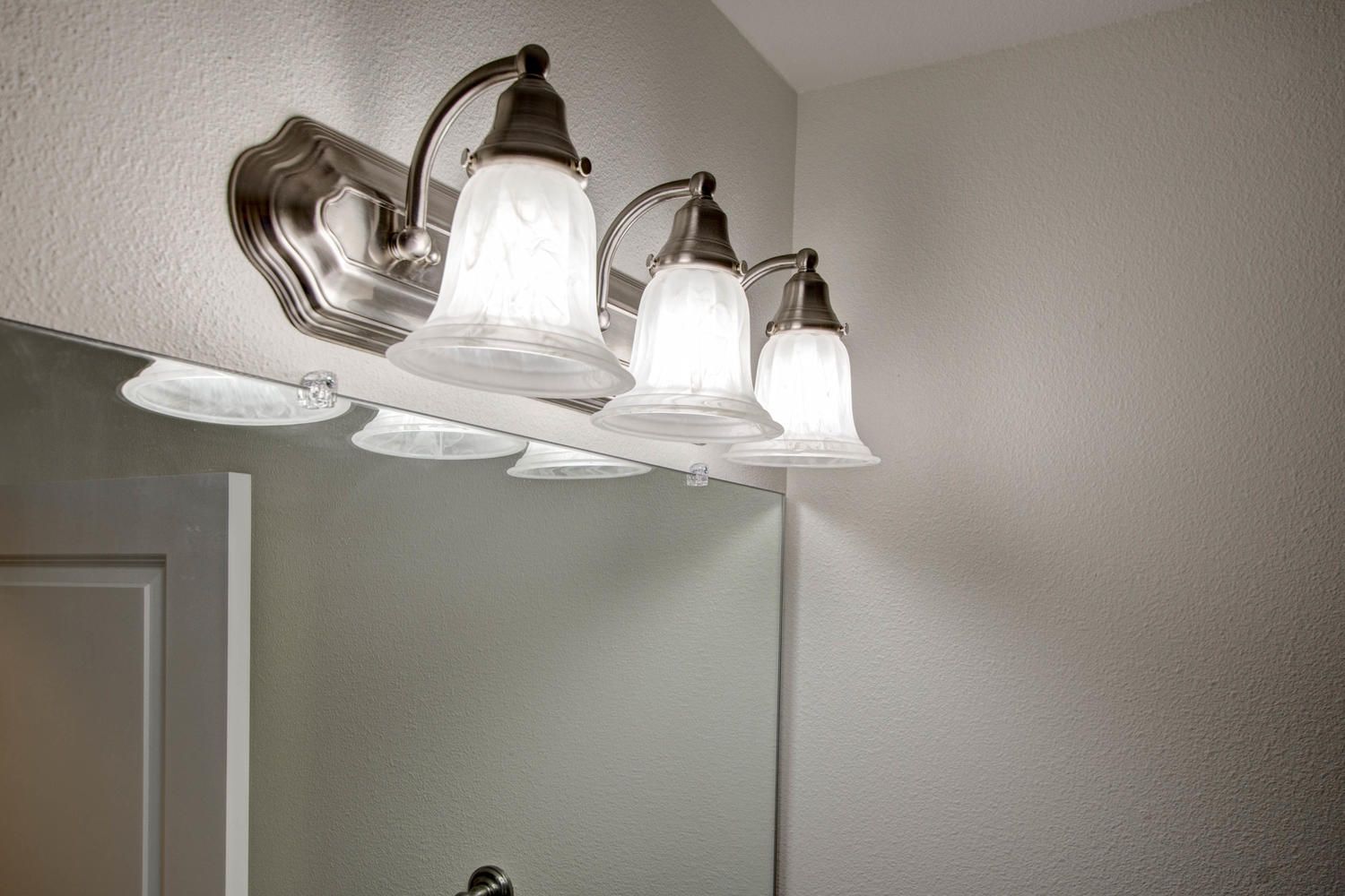 A bathroom mirror with a vanity light above it.