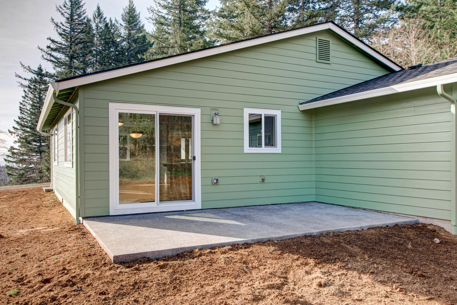 A green house with a patio and sliding glass doors.