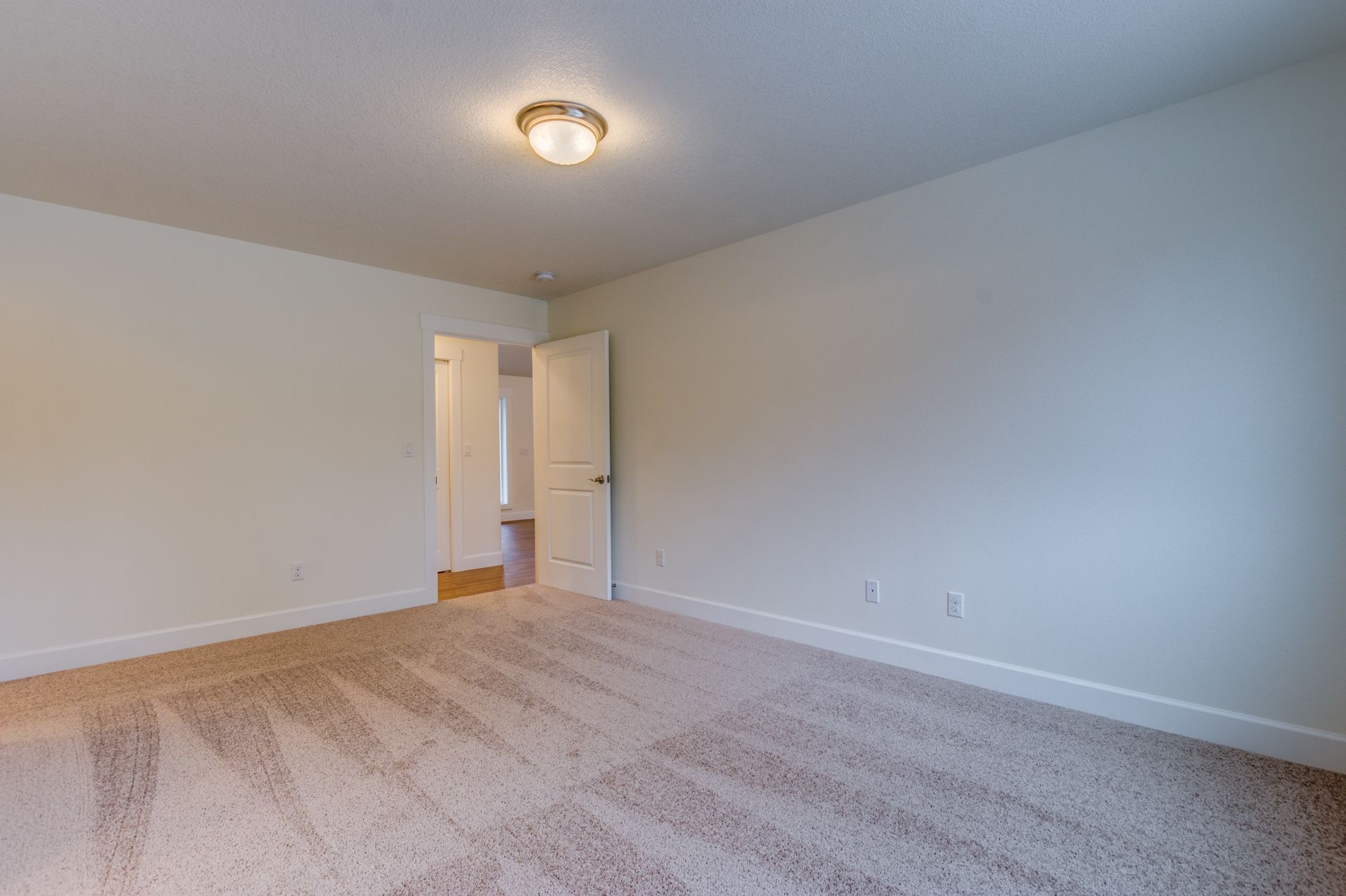 An empty bedroom with a carpeted floor and white walls.