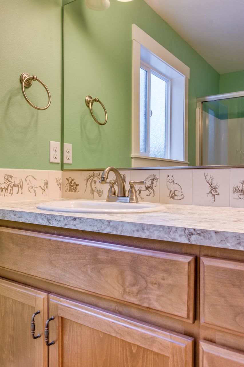 A bathroom with a sink , mirror , and wooden cabinets.