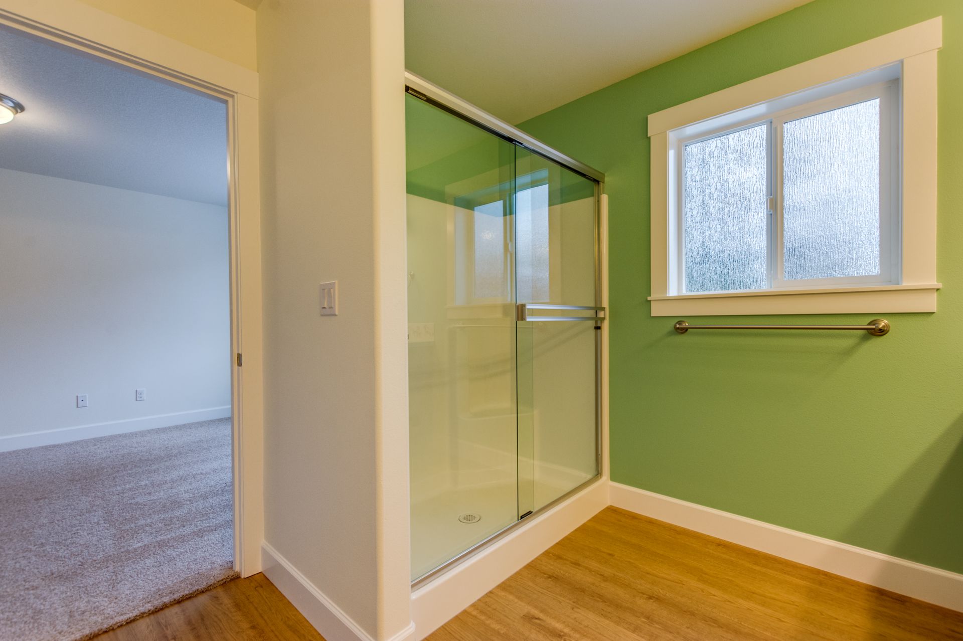 A bathroom with green walls and a sliding glass shower door.